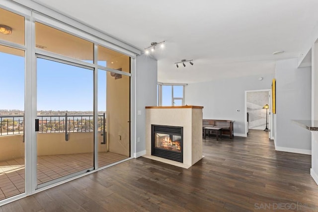 unfurnished living room with a multi sided fireplace and dark wood-type flooring