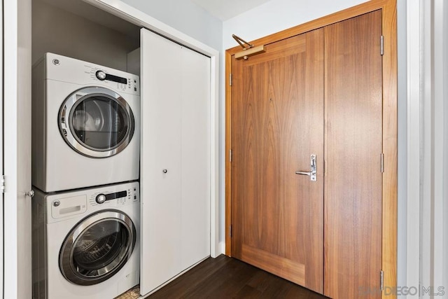 laundry room featuring stacked washer and dryer and dark wood-type flooring