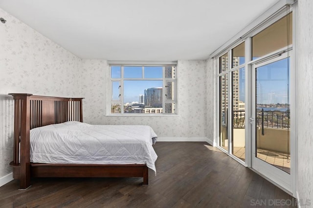 bedroom featuring multiple windows, dark hardwood / wood-style flooring, and access to outside