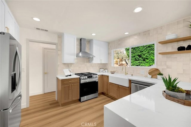 kitchen with white cabinetry, stainless steel appliances, backsplash, wall chimney range hood, and sink