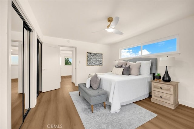 bedroom featuring ceiling fan, hardwood / wood-style flooring, and multiple windows