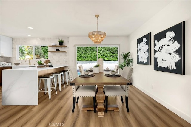 dining area with a notable chandelier, light hardwood / wood-style floors, and sink