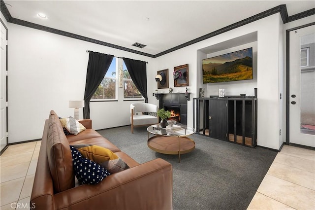 tiled living area with visible vents, a warm lit fireplace, crown molding, and baseboards