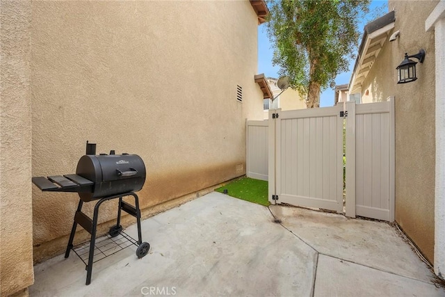 view of patio with a gate, grilling area, and fence