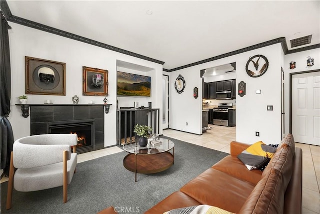 living room featuring a tile fireplace, ornamental molding, and light tile patterned floors