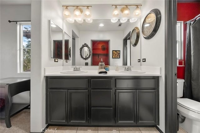 bathroom featuring double vanity, visible vents, toilet, and a sink