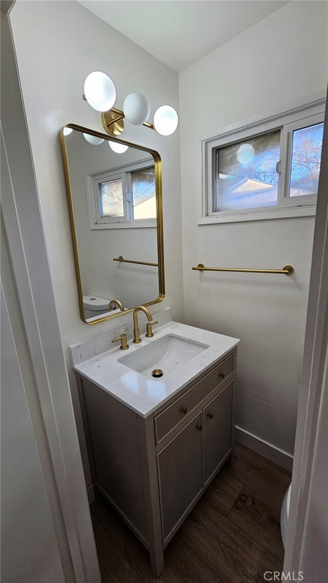 bathroom with toilet, hardwood / wood-style floors, and vanity