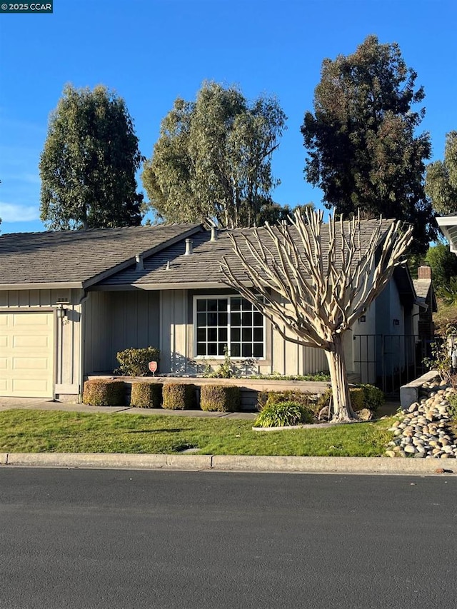 ranch-style house featuring a garage and a front lawn