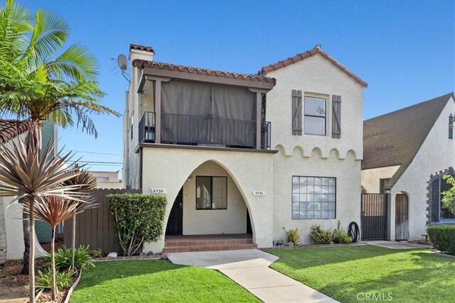 mediterranean / spanish house with a balcony and a front lawn