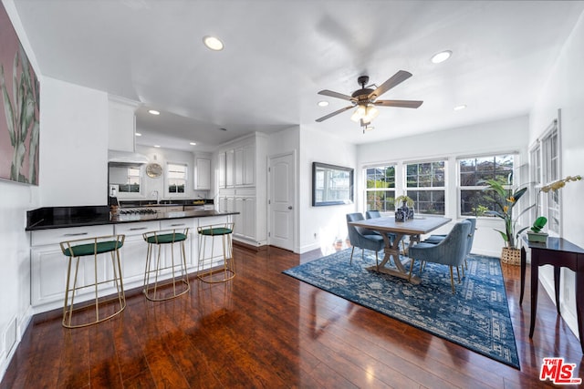 kitchen with ceiling fan, dark hardwood / wood-style floors, kitchen peninsula, sink, and white cabinetry