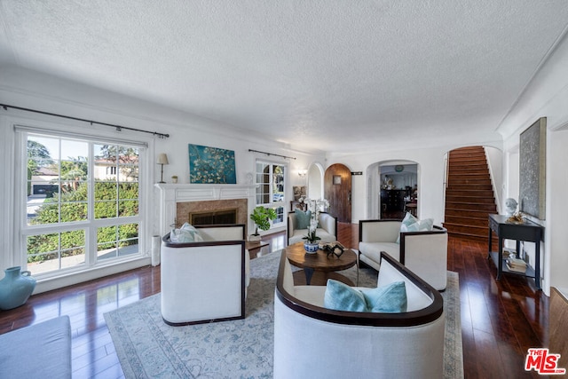 living room featuring a textured ceiling, dark hardwood / wood-style flooring, and a fireplace