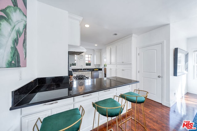 kitchen with dishwasher, dark hardwood / wood-style floors, kitchen peninsula, sink, and white cabinets