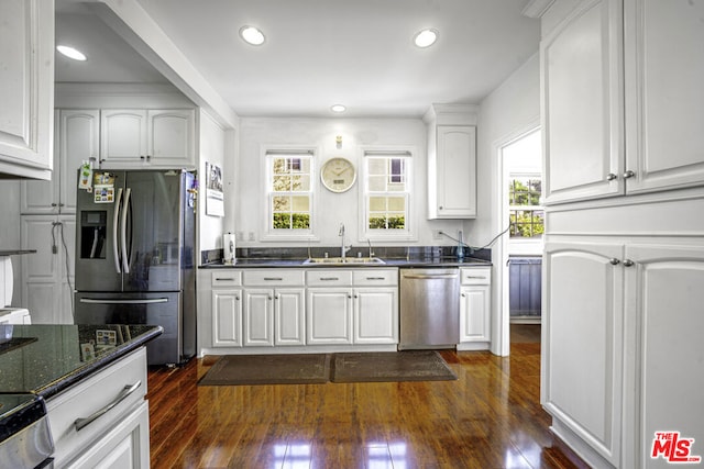 kitchen featuring sink, dark hardwood / wood-style flooring, white cabinetry, stainless steel appliances, and dark stone counters