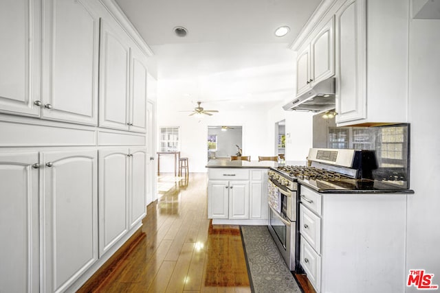 kitchen with ceiling fan, white cabinetry, kitchen peninsula, and range with two ovens