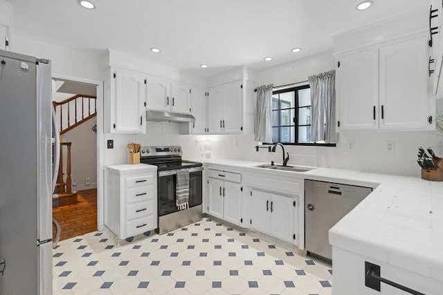 kitchen featuring appliances with stainless steel finishes, tasteful backsplash, white cabinets, and sink