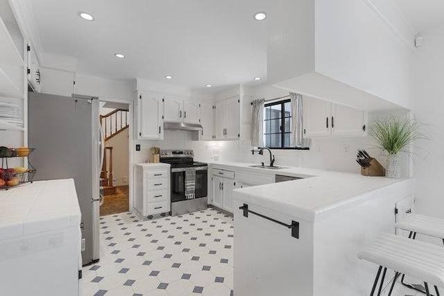 kitchen with sink, white cabinetry, tasteful backsplash, kitchen peninsula, and appliances with stainless steel finishes