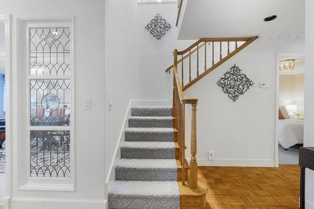 stairs with parquet flooring and crown molding