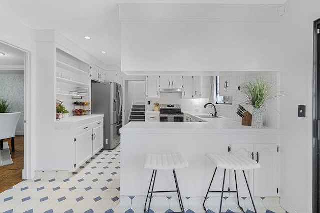 kitchen featuring kitchen peninsula, appliances with stainless steel finishes, a breakfast bar, and white cabinets