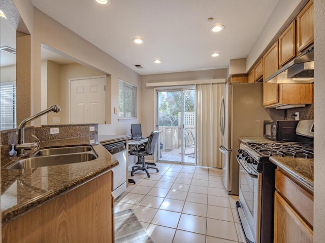 kitchen featuring sink, stainless steel dishwasher, dark stone countertops, range with gas stovetop, and light tile patterned floors