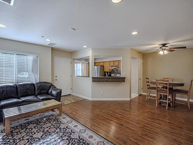 living room featuring ceiling fan, dark hardwood / wood-style flooring, and a textured ceiling