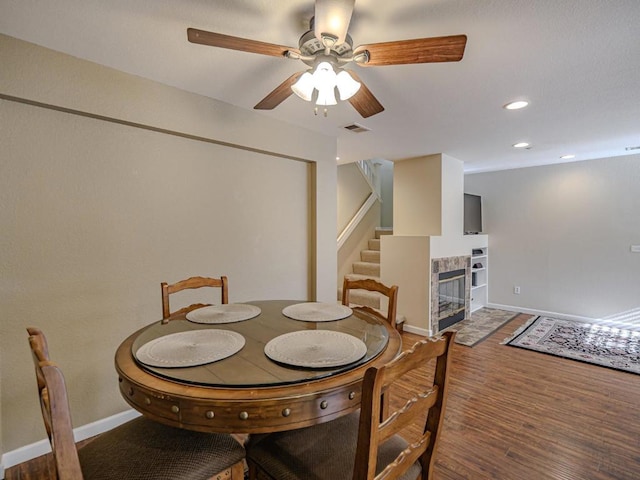 dining area with ceiling fan, a fireplace, and hardwood / wood-style floors