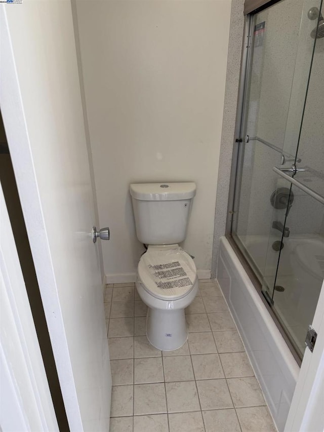 bathroom with toilet, tile patterned flooring, and combined bath / shower with glass door