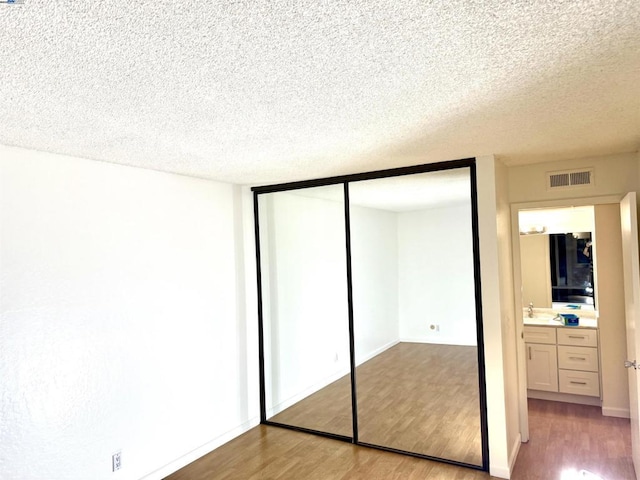 unfurnished bedroom featuring a textured ceiling, a closet, and light hardwood / wood-style flooring