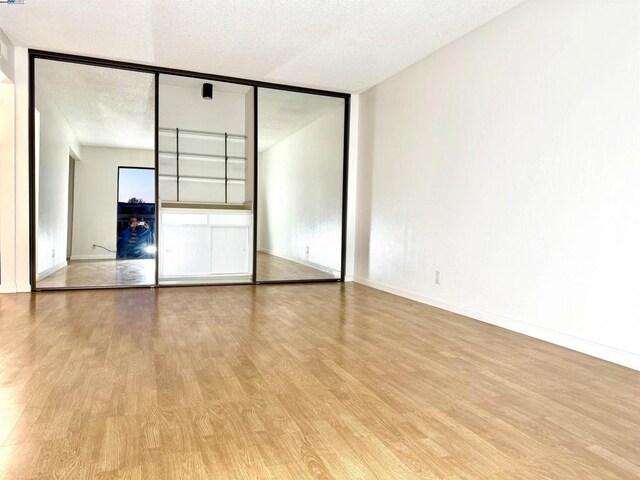 unfurnished bedroom featuring a closet, a textured ceiling, and light hardwood / wood-style floors