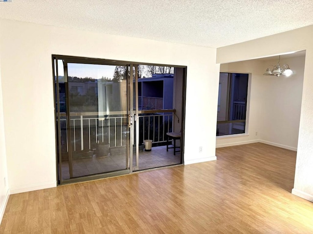 empty room featuring a textured ceiling, a chandelier, and hardwood / wood-style floors