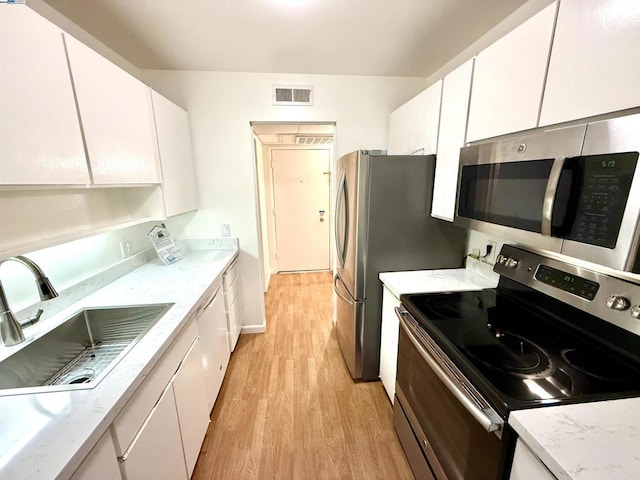 kitchen with white cabinets, sink, stainless steel appliances, and light hardwood / wood-style flooring