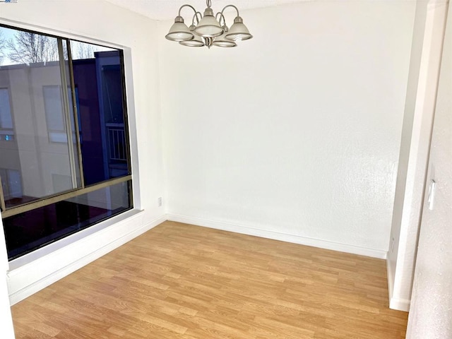 empty room featuring a chandelier and light hardwood / wood-style flooring