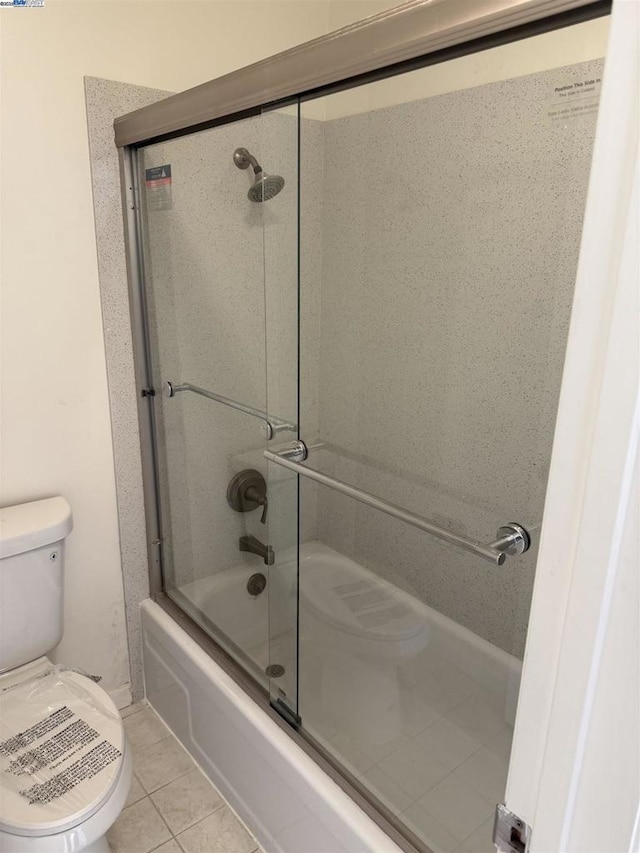 bathroom featuring toilet, tile patterned flooring, and enclosed tub / shower combo