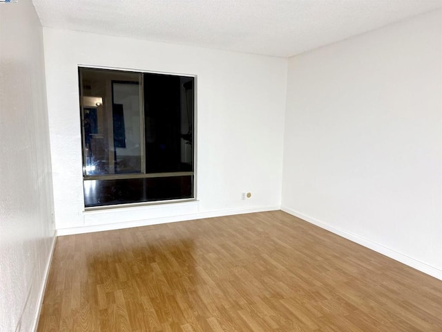 empty room with hardwood / wood-style floors and a textured ceiling