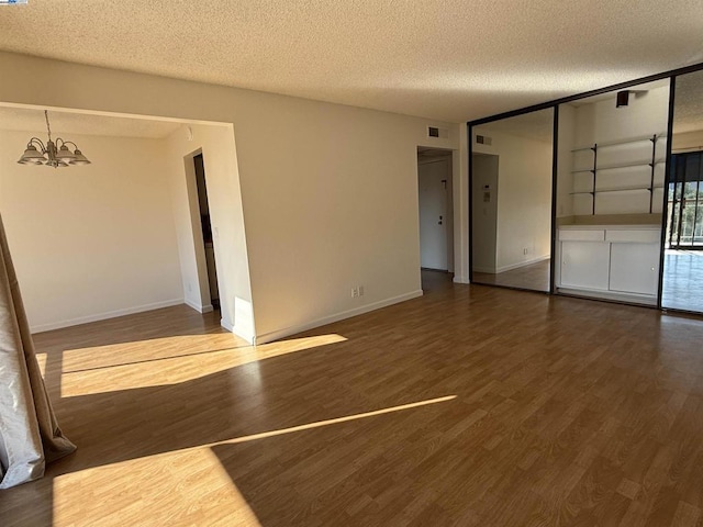 unfurnished room with wood-type flooring, a textured ceiling, and a notable chandelier