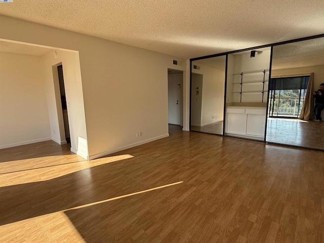 unfurnished living room featuring hardwood / wood-style flooring and a textured ceiling