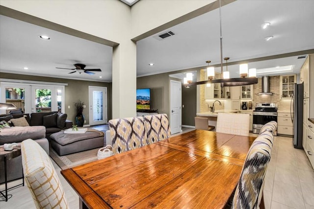 tiled dining area with ceiling fan, french doors, sink, and ornamental molding