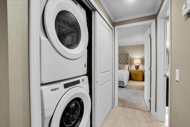 laundry area with light colored carpet, stacked washer / drying machine, and ornamental molding