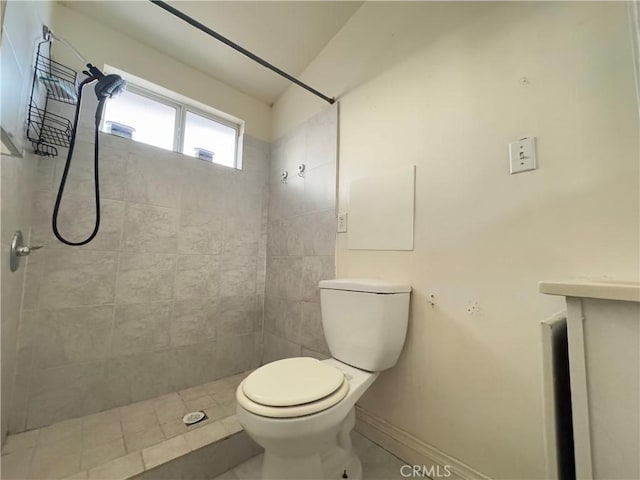 bathroom with toilet, a tile shower, and tile patterned floors