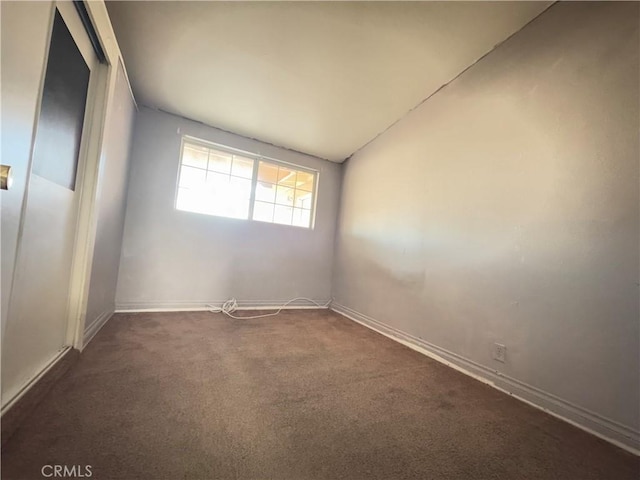 carpeted empty room featuring vaulted ceiling