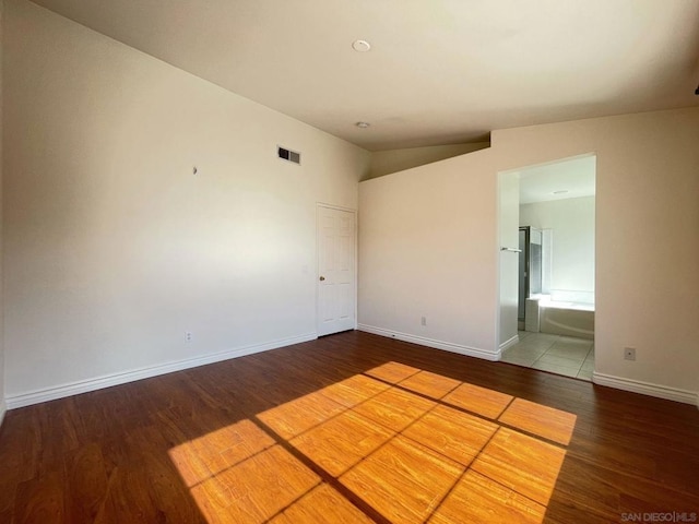 spare room featuring vaulted ceiling and hardwood / wood-style floors