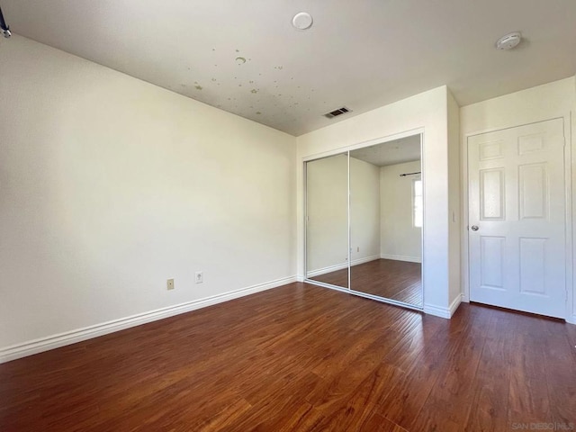 unfurnished bedroom with dark wood-type flooring and a closet