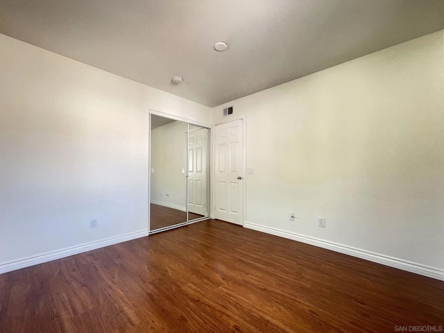 unfurnished bedroom featuring a closet and dark hardwood / wood-style floors