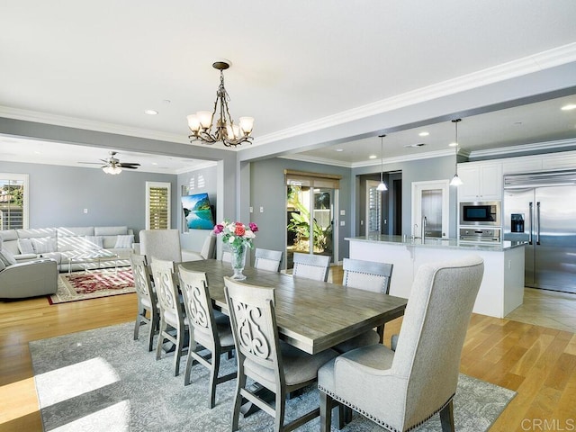 dining space featuring ceiling fan with notable chandelier, ornamental molding, and light hardwood / wood-style floors