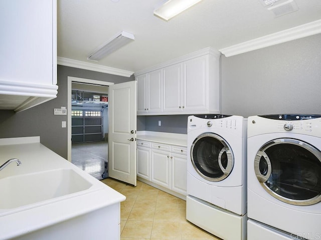 laundry room with sink, light tile patterned flooring, crown molding, washer and clothes dryer, and cabinets