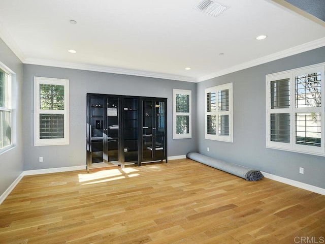 spare room featuring plenty of natural light, light hardwood / wood-style flooring, and ornamental molding