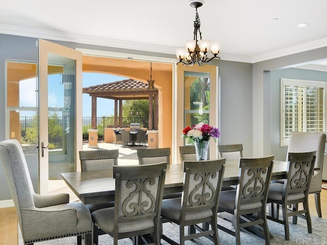 dining room with wood-type flooring, a wealth of natural light, crown molding, and a chandelier