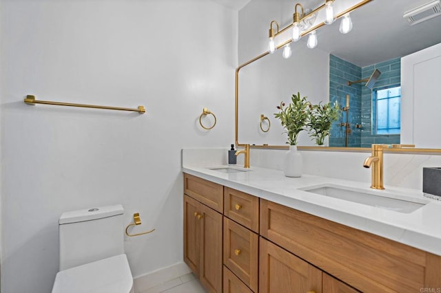 bathroom featuring toilet, tile patterned flooring, tiled shower, and vanity