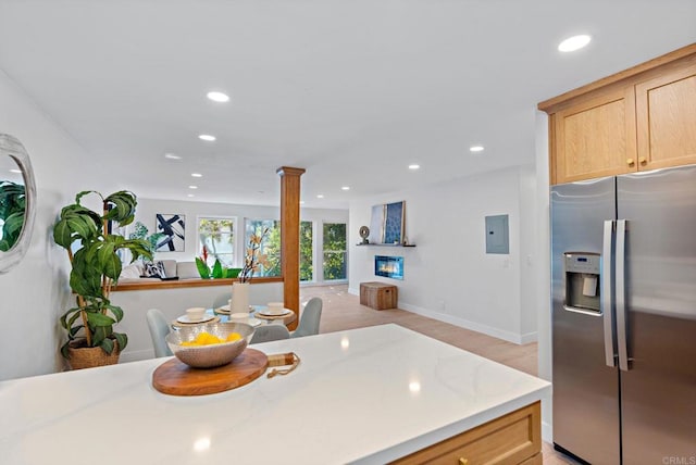 kitchen with ornate columns, electric panel, light brown cabinetry, and stainless steel fridge