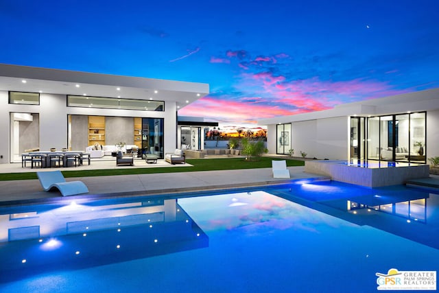 pool at dusk with a patio area and outdoor lounge area