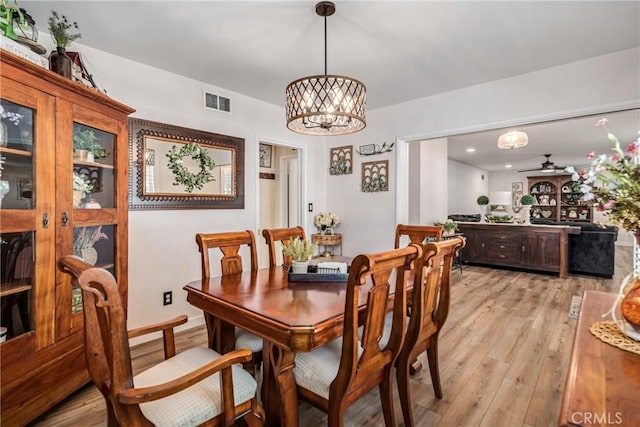 dining space with a chandelier, visible vents, and light wood-type flooring